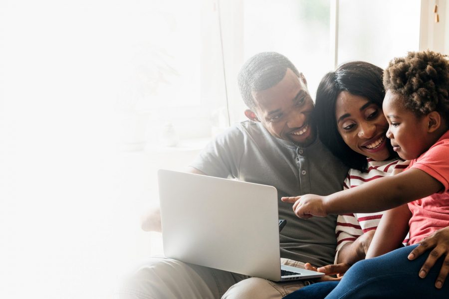 Happy black family and toddler pointing at a laptop screen design space